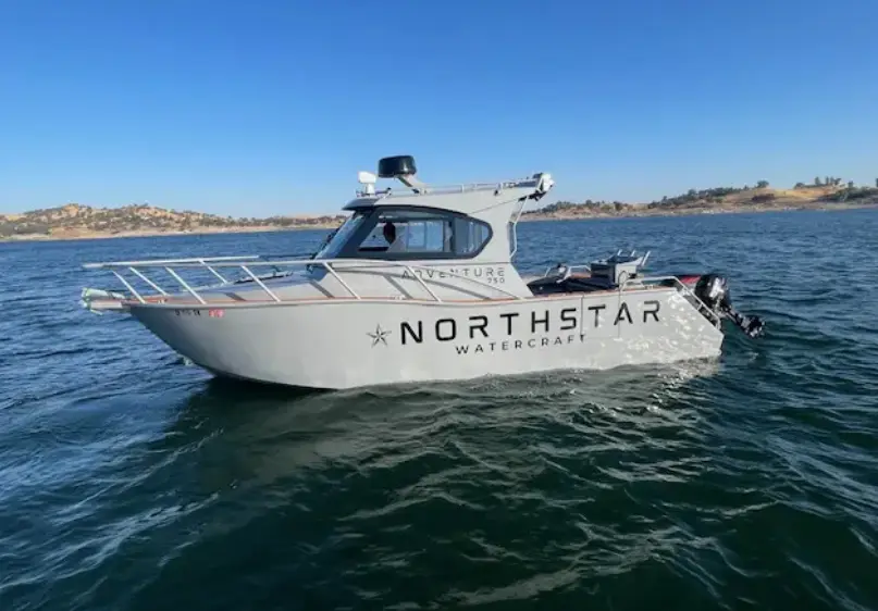 A white boat is in the water near some land.