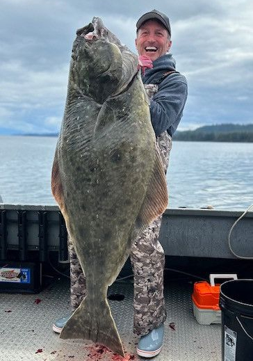 A man holding a large fish on top of a boat.